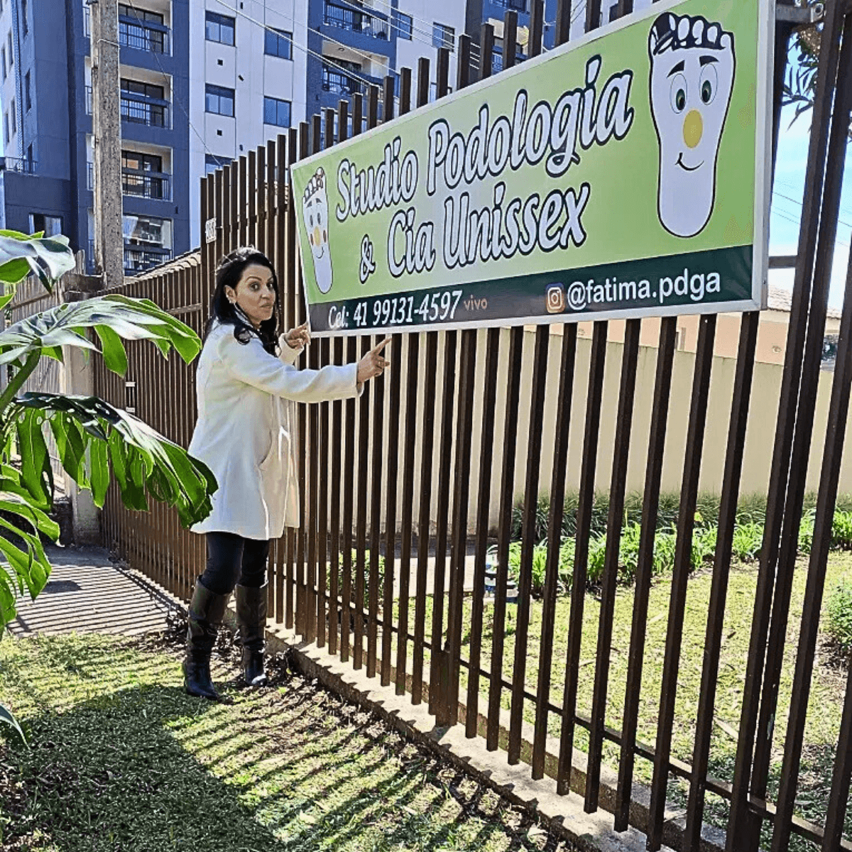 Podóloga Fátima Barros ao lado do banner do consultório